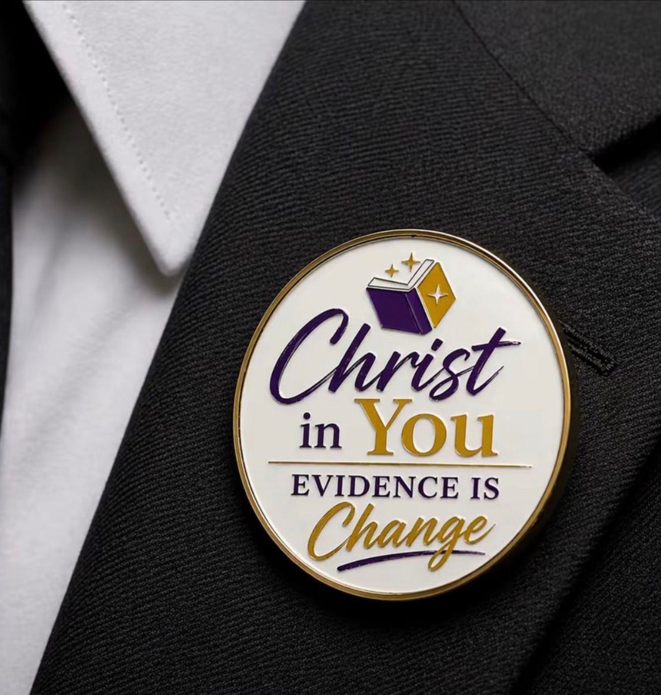 Round gold Kaleo Fellowship lapel pin worn on a dark jacket